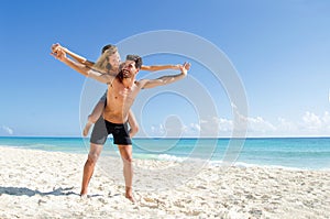 Couple piggy back ride at the beach