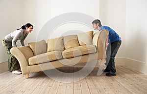 Couple Placing Sofa In Living Room Of New Home photo