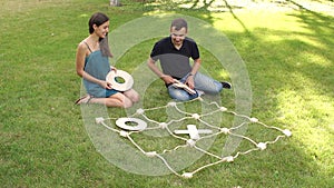 Couple play big tic tac toe while sitting on grass