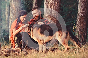 Couple play with german shepherd dog outdoor, forest background.
