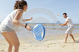 couple playing beach tennis game on sand