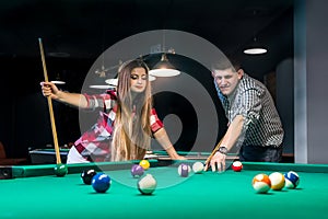 Couple playing billiard, woman looking after boyfriend