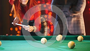 A couple playing billiards. A woman aiming and hit the ball