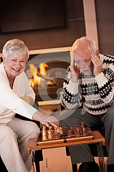 Couple playing chess in cosy living room