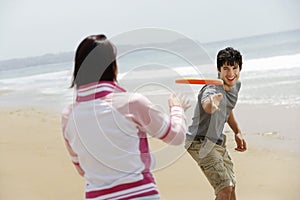 Couple Playing Frisbee On Beach