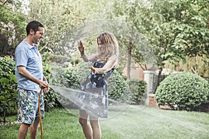 Couple playing with a garden hose and spraying each other outside in the garden