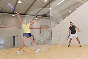 couple playing squash in indoor court