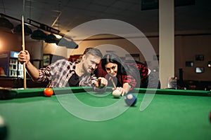 Couple plays in billiard room, male player aiming