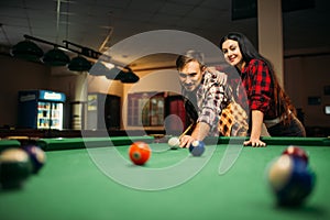 Couple plays in billiard room, male player aiming