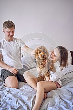 a couple plays with a cockapoo girl on a bed, minimalism