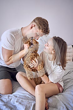 a couple plays with a cockapoo girl on a bed, minimalism