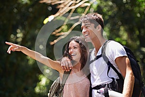 Couple, point and happy for hiking in jungle with smile for thinking, holiday and ideas on path. Man, woman and bag for