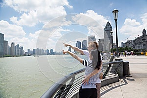 Couple pointing at cityscape while standing on promenade in Shanghai