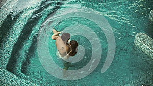 Couple in pool bathing together. Above view young family relaxing in pool.