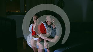 couple with popcorn watching tv at home