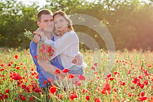 Couple among poppy field embracing and smiling