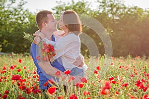 Couple among poppy field embracing and smiling