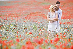 Couple in poppy field embracing and smiling