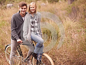 Couple, portrait and field with retro bicycle on holiday, adventure or date with sustainable transport. Man, woman and
