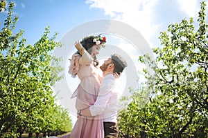 Couple portrait of a girl and guy looking for a wedding dress, a pink dress flying with a wreath of flowers on her head on a backg