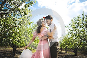 Couple portrait of a girl and guy looking for a wedding dress, a pink dress flying with a wreath of flowers on her head on a backg