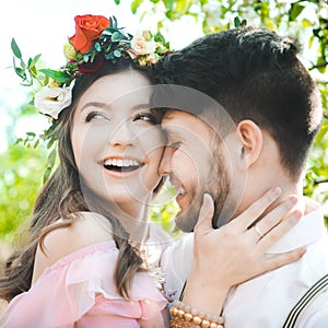 Couple portrait of a girl and guy looking for a wedding dress, a pink dress flying with a wreath of flowers on her head on a backg