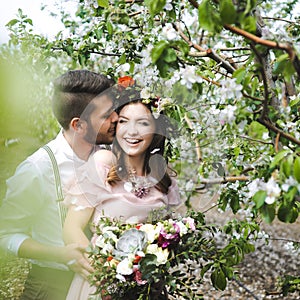 Couple portrait of a girl and guy looking for a wedding dress, a pink dress flying with a wreath of flowers on her head on a backg