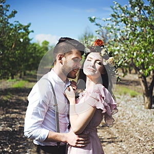 Couple portrait of a girl and guy looking for a wedding dress, a pink dress flying with a wreath of flowers on her head on a backg