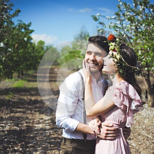 Couple portrait of a girl and guy looking for a wedding dress, a pink dress flying with a wreath of flowers on her head on a backg