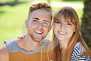 Couple, portrait and listening to music with earphones in garden, park or relax in summer with technology. Happiness