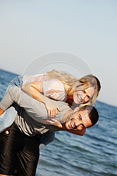 Couple, portrait and piggyback on vacation, ocean and peace at beach or game by blue sky. People, happy and tropical