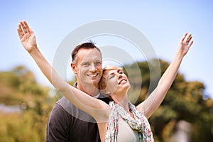 Couple, portrait and smile with love outdoors for honeymoon vacation, together and arms up for freedom. Man, woman and