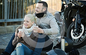 Couple posing near motor bike with sandwitches and coffee