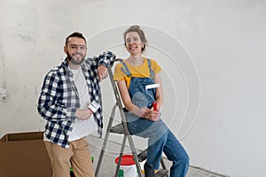 couple posing during repair works painting wall together and standing with tools