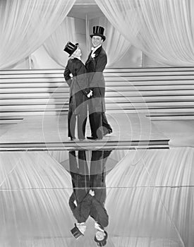 Couple posing in tuxedos and reflection photo