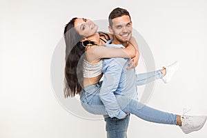 Couple posing on white background - man holding woman on his back