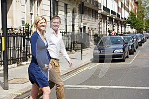 Couple With Pregnant Wife Crossing City Road