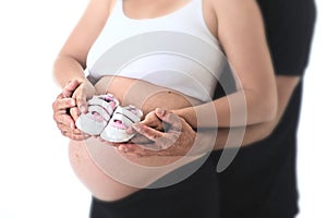 Couple with pregnant woman holding with hands together newborn baby shoes for upcoming daughter