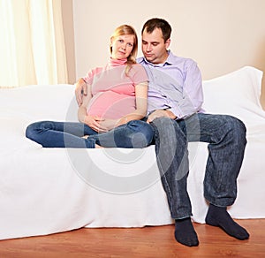 Couple With Pregnant Woman Relaxing On Sofa Together
