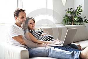 A Couple With Pregnant Woman Using Laptop Computer Together