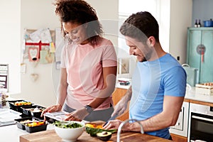 Couple Preparing Batch Of Healthy Meals At Home In Kitchen Together