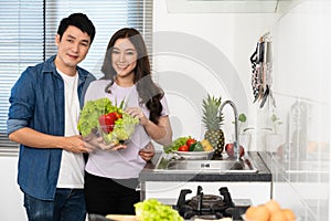 Couple with preparing vegetables to cooking together in the kitchen at home. man is hugging woman photo