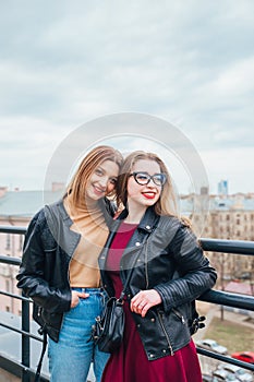 Couple of pretty women together in cityscape . Two joyful beautiful girls on roof . Beautiful city view