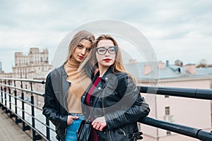 Couple of pretty women together in cityscape . Two joyful beautiful girls on roof . Beautiful city view