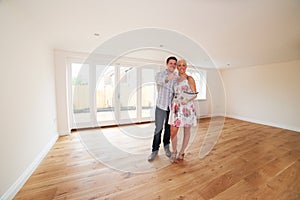 Couple With Property Details Looking Around New Home