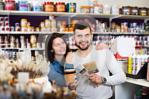 Couple purchasing tools for house improvements in paint supplies store