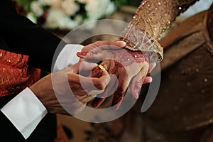 A Couple put on a ring Gold Wedding Rings on Their Hand