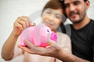 Couple putting coin into Pink Piggy Bank.