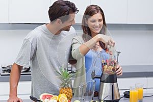 Couple putting fruits into blender