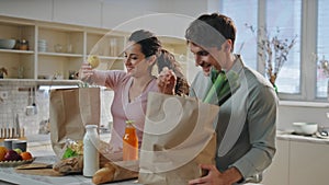 Couple putting shoppings kitchen table from grocery store closeup. Happy spouses photo